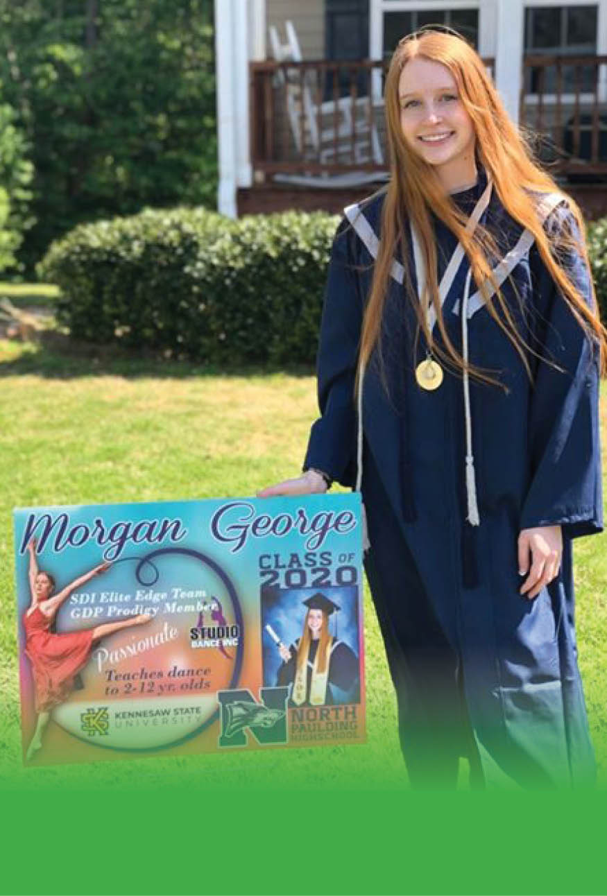 2020 high school graduate smiling and standing next to her celebratory yard sign